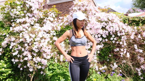 Full length of young woman standing by flower tree