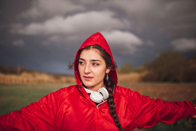 Beautiful woman standing on field against cloudy sky