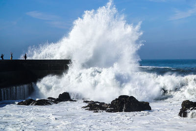 Waves splashing on shore against the sky