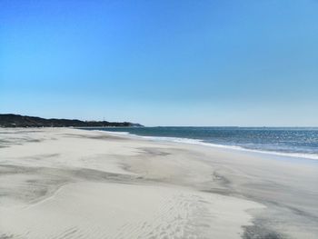 Scenic view of beach against clear blue sky