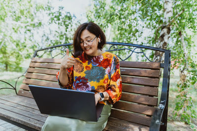 Outdoor office with cheerful woman conducting video meetings on laptop in nature