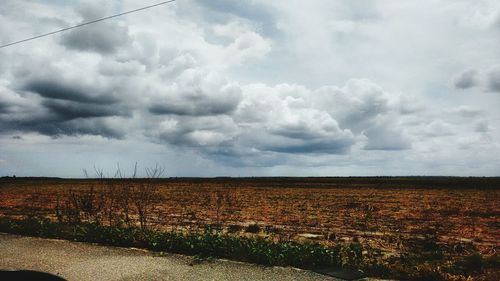 Scenic view of field against storm clouds