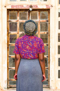 Rear view of woman standing against door of building