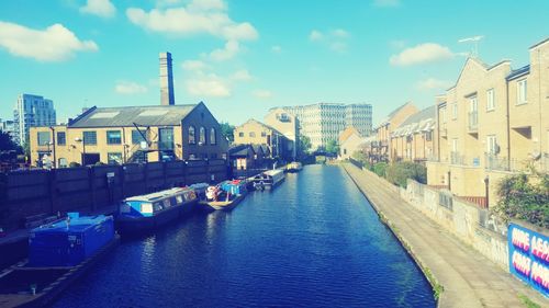 Canal amidst buildings in city against sky