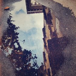 Building and sky reflecting in puddle on street
