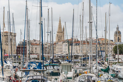 Sailboats moored in harbor against buildings in city