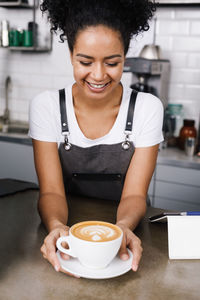 Young woman holding coffee cup in kitchen