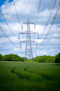 Ylon power electricity electrical distribution cable across field with blue sky and white clouds