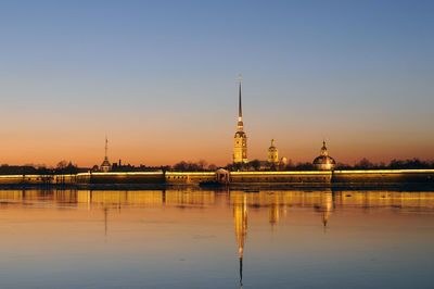 Reflection of building in city against sky during sunset