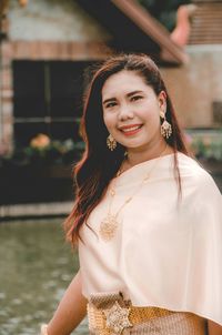 Portrait of smiling woman in traditional clothing against pond