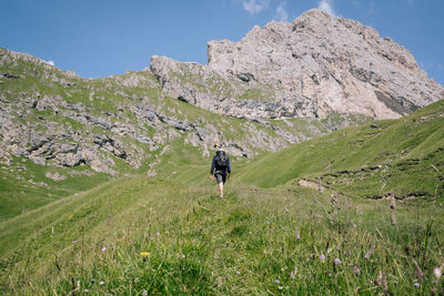 Rear view of man walking on mountain against sky