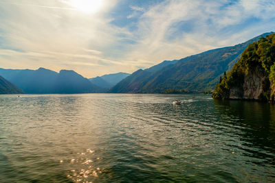 Scenic view of sea by mountains against sky