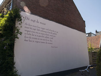 Low angle view of text on wall against building