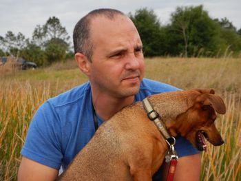 Mid adult man with brown dog on grassy field