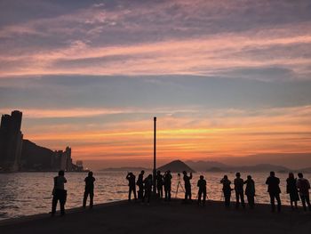 Silhouette people standing at beach during sunset