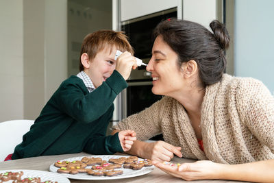 Mother and son preparing food on table at home