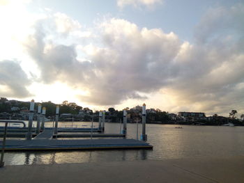Bridge over river by buildings in city against sky