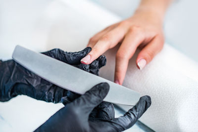 Close-up of woman doing nail art of customer at table