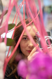 Portrait of woman holding camera amidst plants