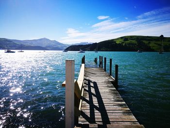 Pier over sea against clear blue sky