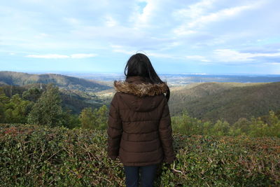 Rear view of woman standing on field against sky