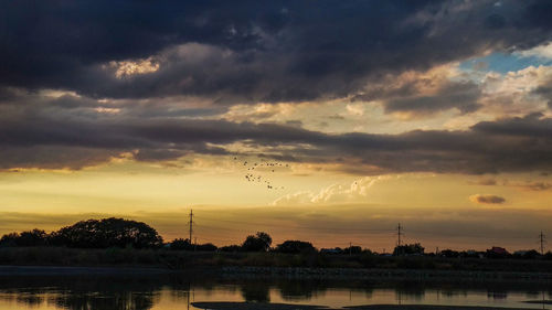 Scenic view of river against sky at sunset