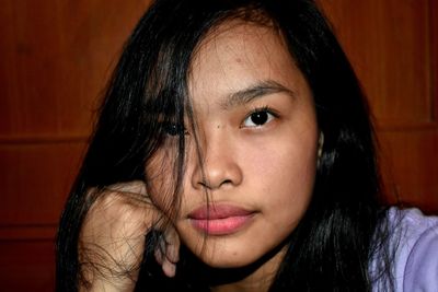 Close-up portrait of young woman against wall