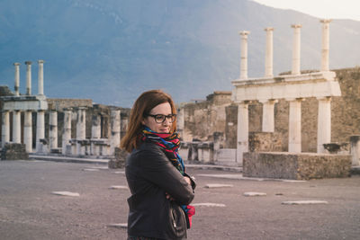 Side view of young woman standing against built structures