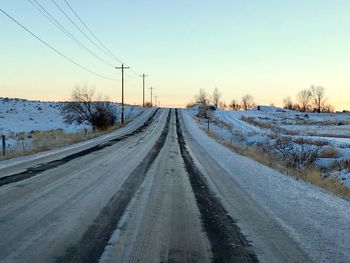 Snow covered railroad track against sky during winter