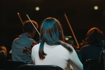 Rear view of woman playing violin during event