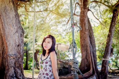 Portrait of young woman standing by swing