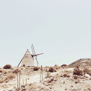 Traditional windmill on desert against clear sky