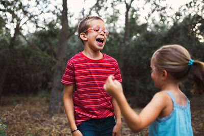 Boy and girl laughing while playing in forest