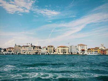 Residential buildings by sea against sky