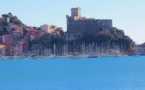 Buildings by sea against clear sky