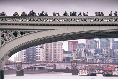 Bridge over river in city against sky