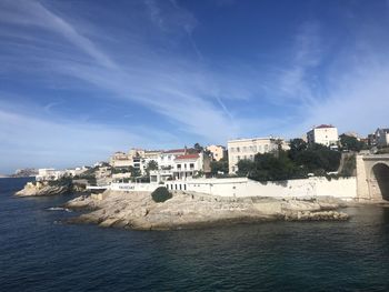 Buildings by sea against blue sky