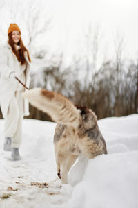 Woman with dog walking on snow