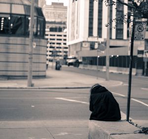 Rear view of man on sidewalk by road in city