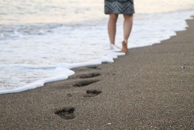 Low section of man standing on beach