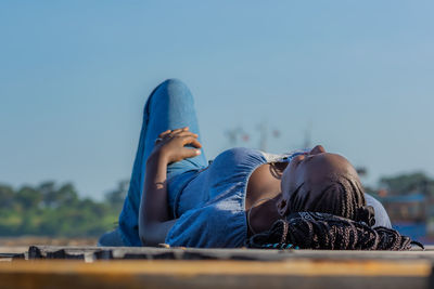 Midsection of woman resting against blue sky
