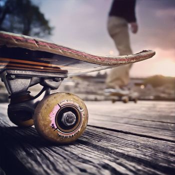 Close-up of skateboard with blurred man skateboarding behind