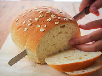 Woman slicing homemade bread bakery on wooden cutting board.