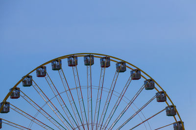 Low angle view of ferris wheel against clear blue sky