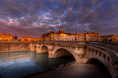 Arch bridge over river against cloudy sky in paris