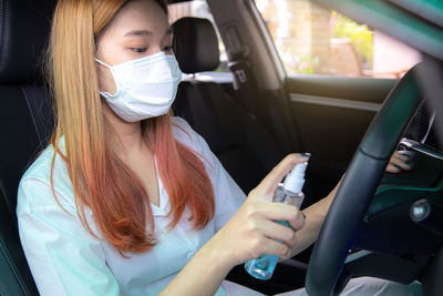 Portrait of woman holding mobile phone while sitting in car