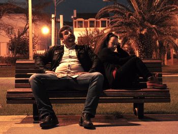 Close-up of friends sitting on bench at night