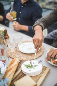 High angle view of man cutting mozzarella over cutting board at building terrace during party