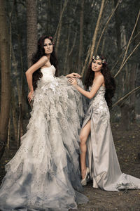 Full length portrait of happy woman standing in forest