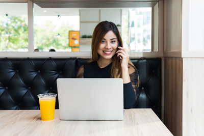 Smiling businesswoman using laptop while sitting at cafe